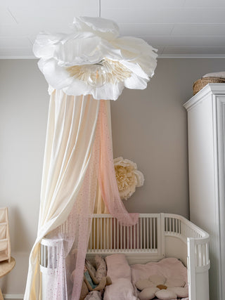 Nursery room with a crib, decorative canopy, and large flowers by MINICAMP